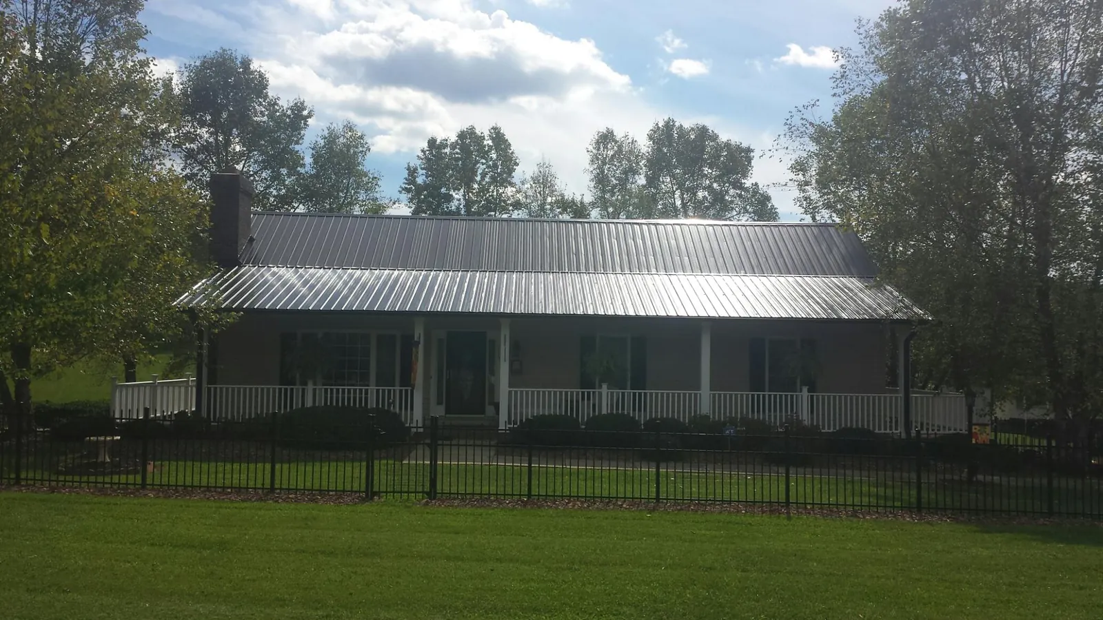 Gray metal roof on a brick ranch with a full width front porch — Gutter Guard Installation work by our crew in Ohiopyle