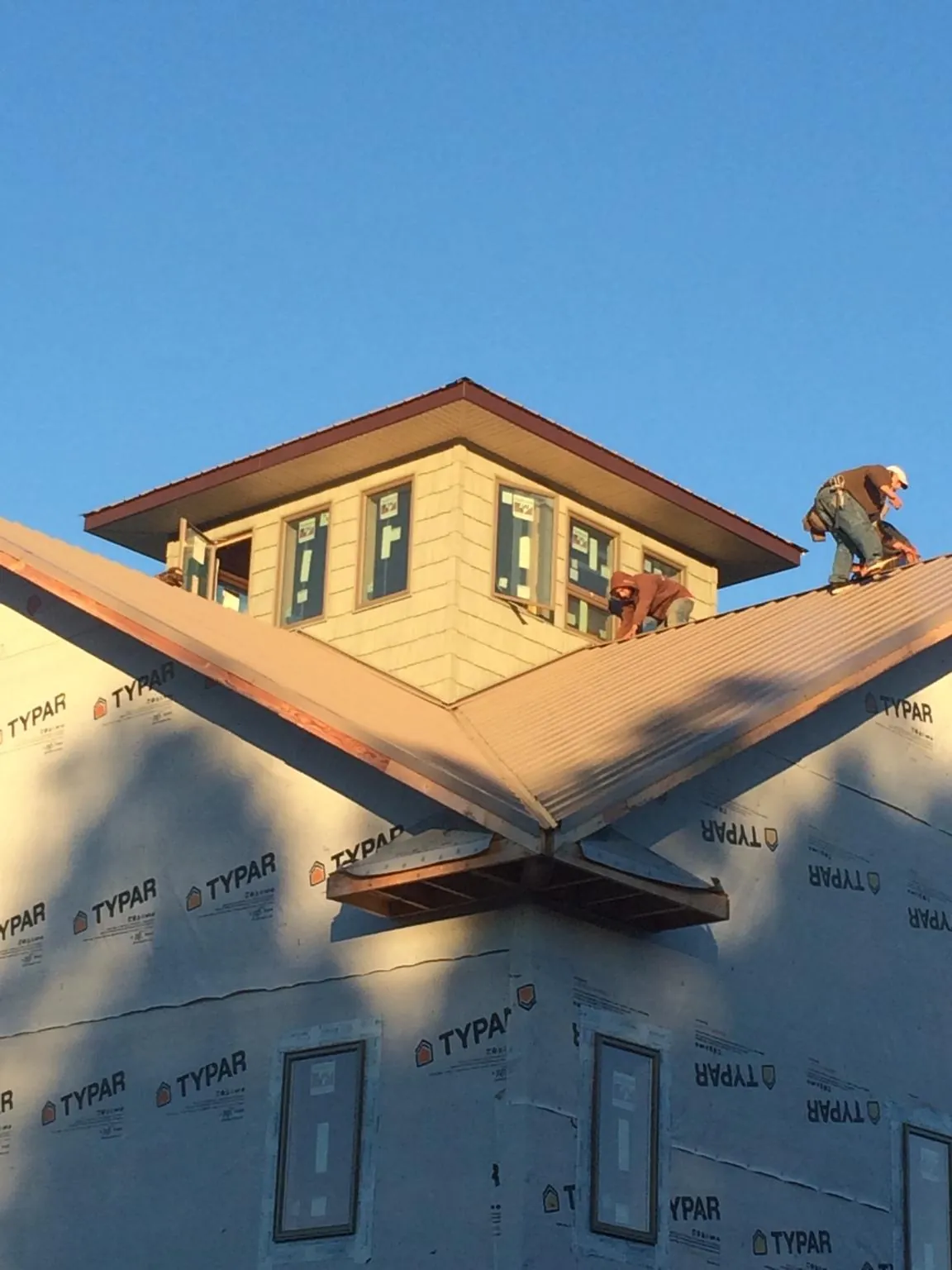 Roofers working around a rooftop cupola on a new metal roof at sunset — Roof Waterproofing in Ohiopyle by Roofing Brothers
